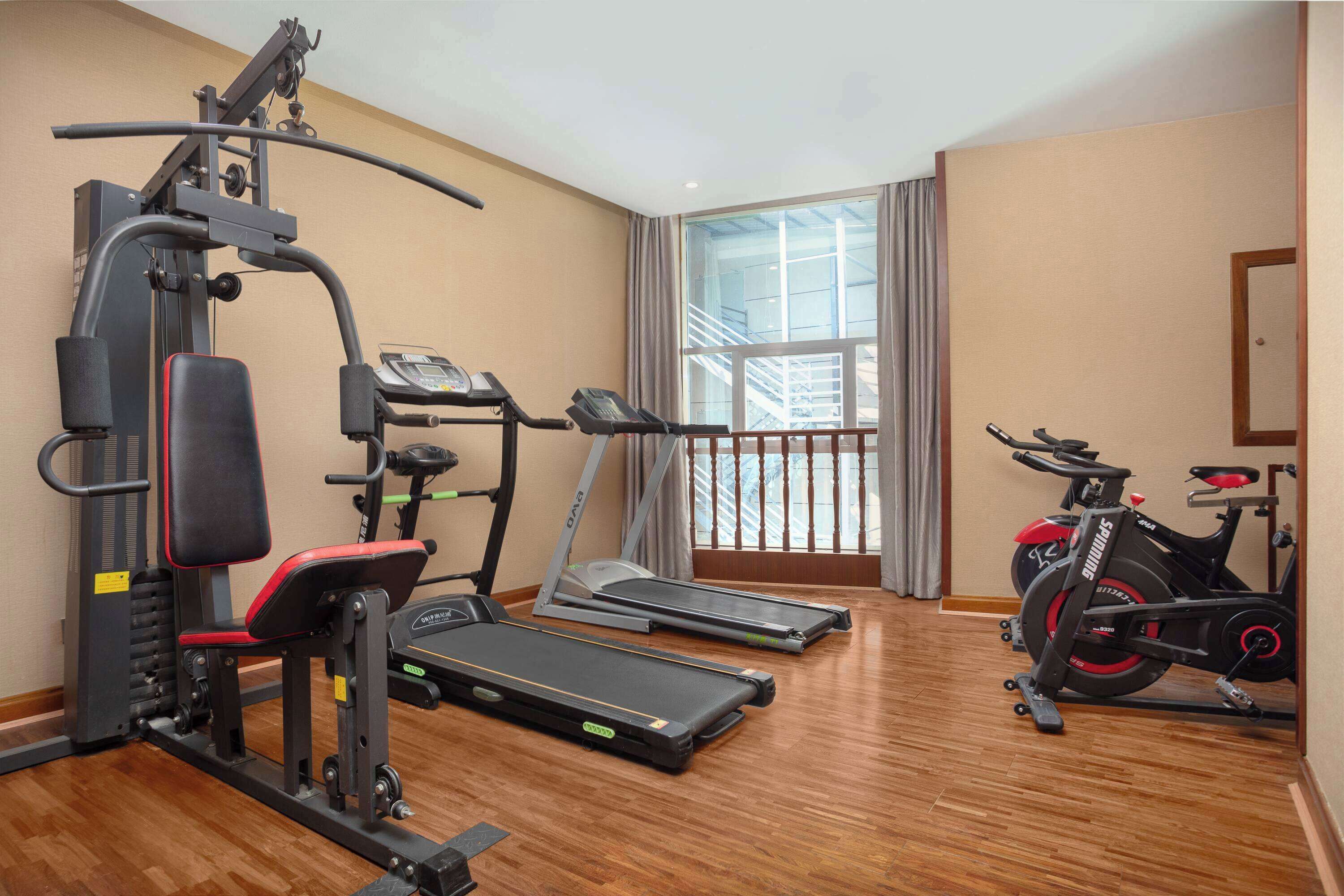 Un gimnasio con cintas de correr, una bicicleta estática y máquinas de pesas.