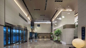 Un hall d’entrée spacieux, doté d’un sol en marbre poli, de portes en verre et d’un comptoir d’accueil.