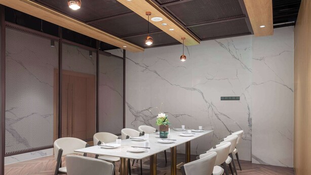 Une salle de conférence avec une longue table, des chaises blanches et un vase décoratif.