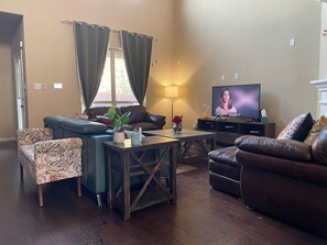 Una sala de estar con sofá, sillón, mesa de centro y televisor.