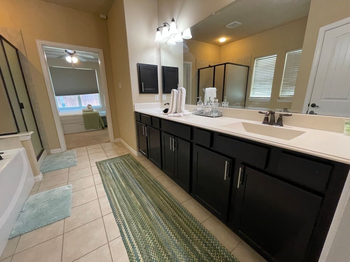 A modern bathroom with a large sink, dark cabinets, and a mirror above the counter.