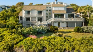 Une grande maison à étages, dotée de nombreux balcons et d’un jardin bien entretenu.