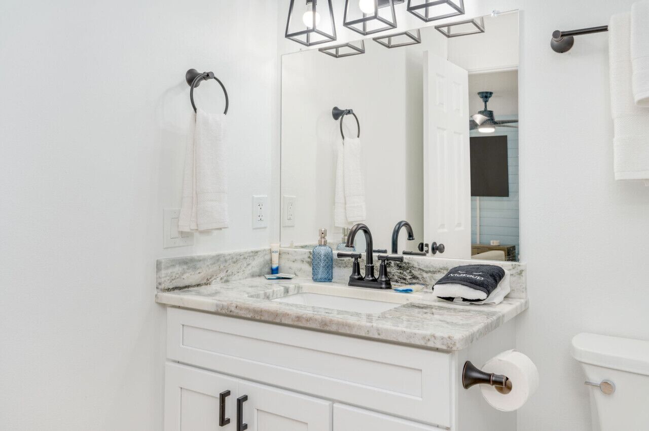 A bathroom with a white sink, black faucet, and a mirror above it.