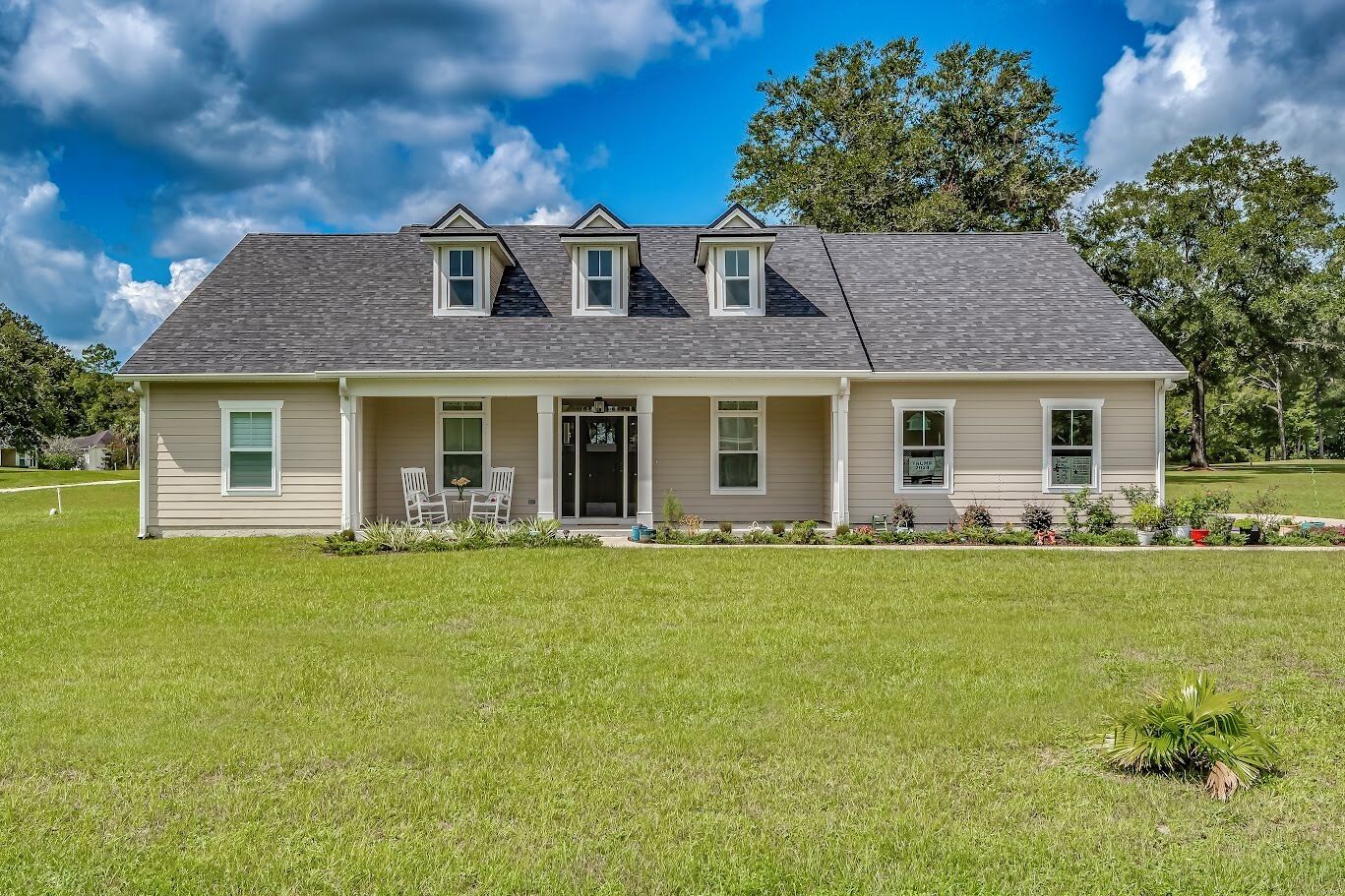 A two-story house with a front porch, a covered entryway, and a small garden area.