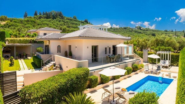 Una villa moderna con piscina, mobiliario de exterior y un jardín exuberante.