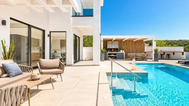 A modern outdoor pool area with a dining set and a kitchen area visible through glass doors. - Villa Vatia 3 - Three Bedroom Villa, Sleeps 8 (Ionian Islands)