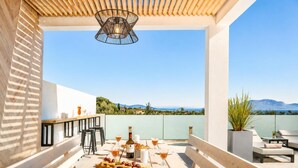 An outdoor patio with a wooden table set for dining, a hanging light fixture, and a view of the landscape. - Villa Vatia 3 - Three Bedroom Villa, Sleeps 8 (Ionian Islands)
