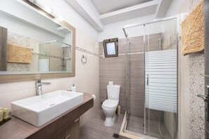 Une salle de bain moderne avec un grand lavabo blanc, des toilettes et une douche séparée par une paroi de verre.
