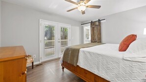 A bedroom with a wooden bed, a ceiling fan, and a sliding glass door leading to an outdoor area.