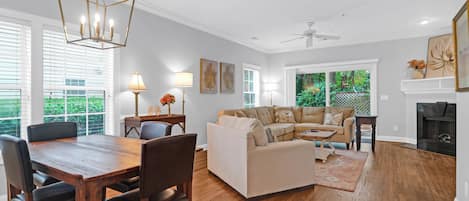 A spacious living room with a wooden dining table, a beige sofa, and a fireplace.