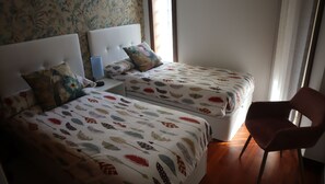 A bedroom with two beds, each with feather-patterned bedding, a nightstand with a lamp, and a chair. - Pool and sea view accommodation 50 m sea (Ovar)