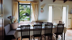 A dining area with a table set for four, a bench, and a view of greenery outside. - Garden Tower Relais Sorrento (Sorrento)