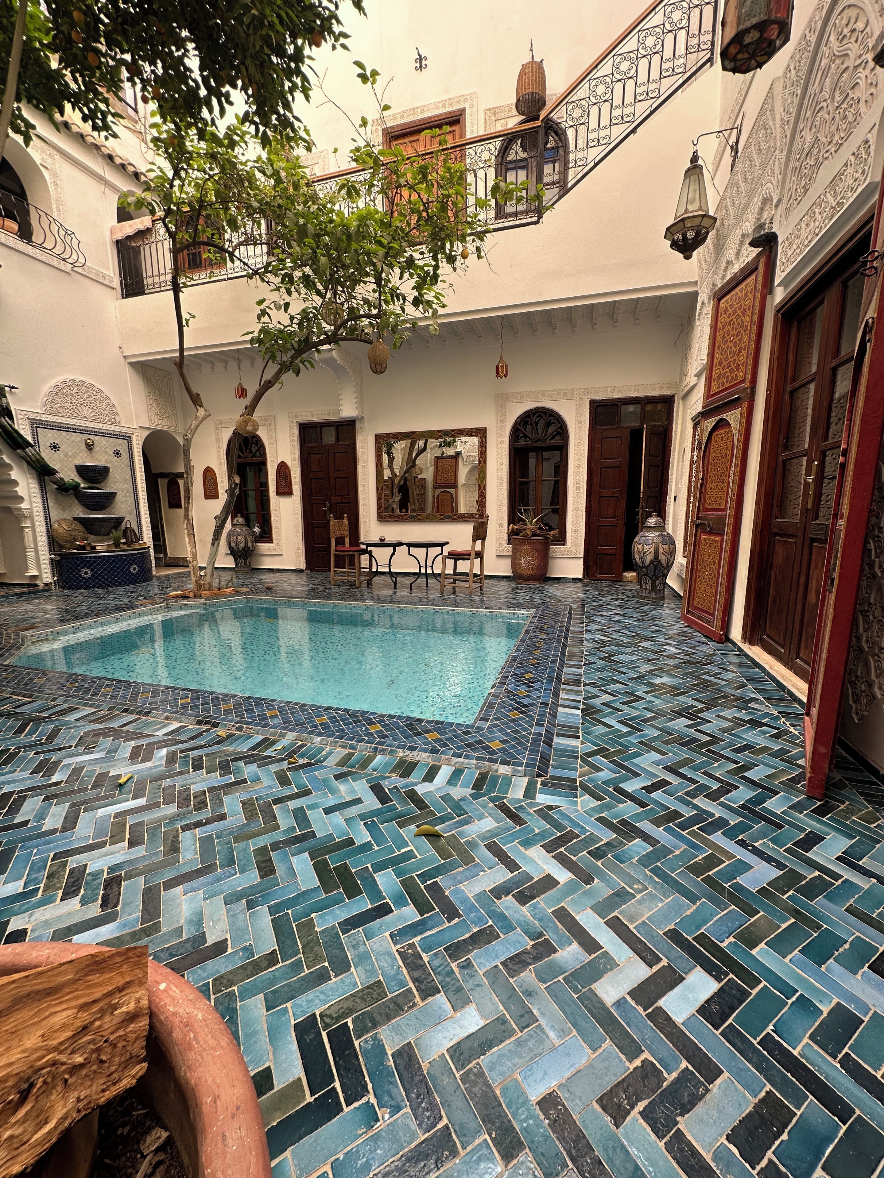 Un cortile con piscina, pavimento piastrellato e zona pranzo.