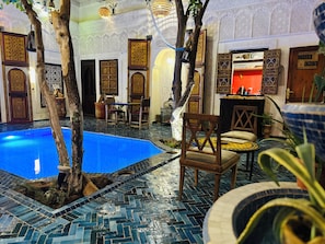 Una piscina interior con suelo de baldosas, rodeada de puertas y muebles ornamentados.