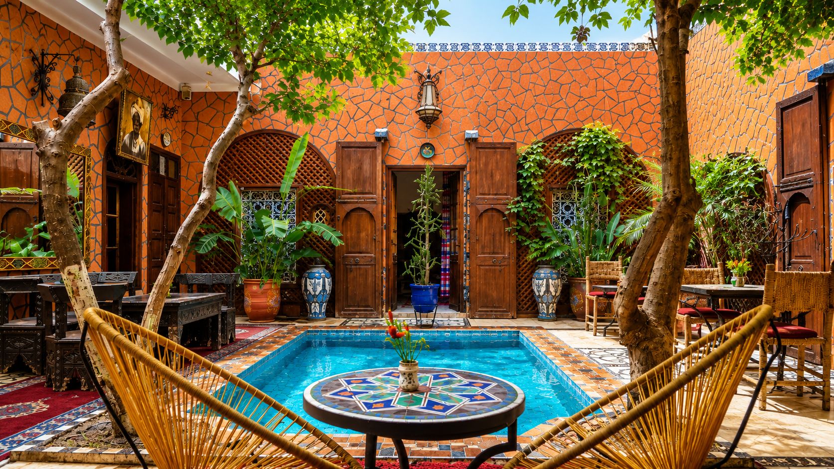A courtyard with a swimming pool, wooden doors, and potted plants.