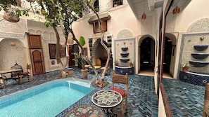 Un patio con piscina, suelo de baldosas y elementos arquitectónicos tradicionales.