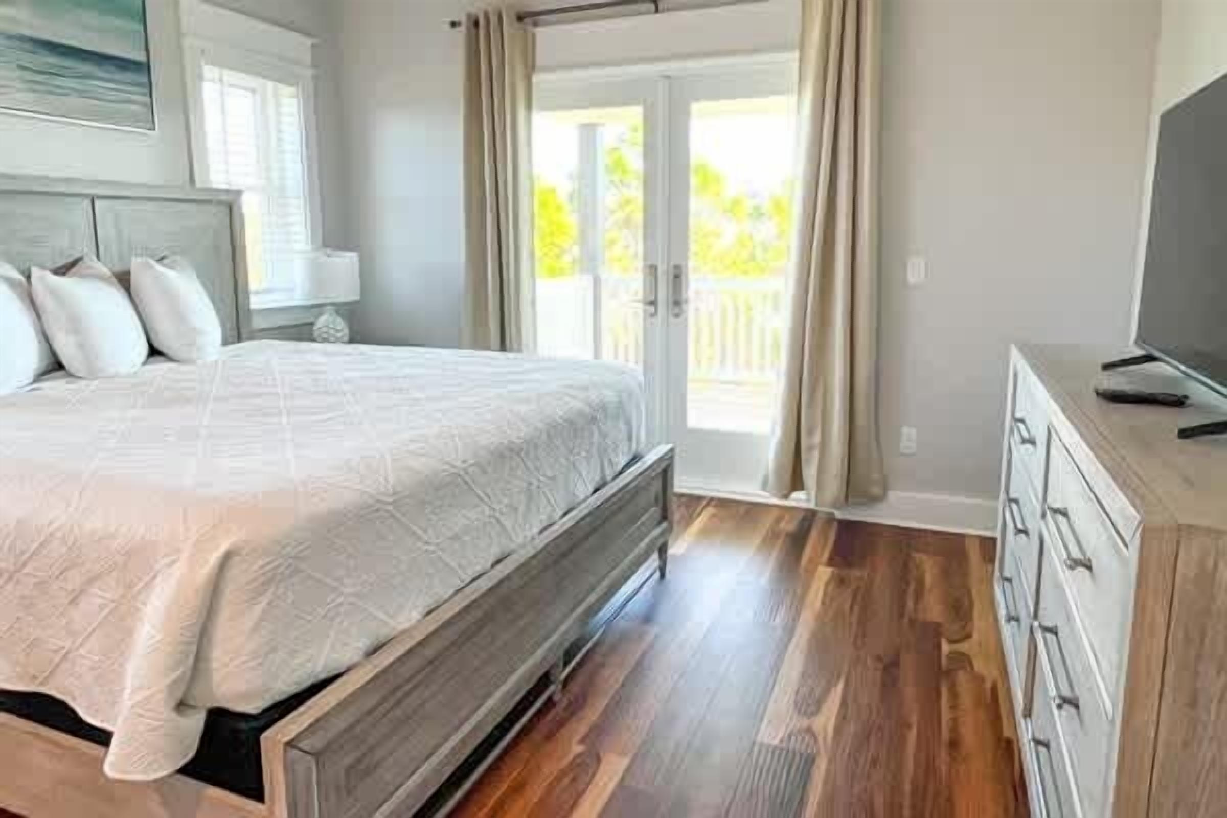 A bedroom with a bed, a dresser, and a television.