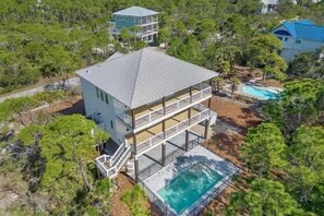 A multi-story house with a pool, surrounded by trees. - Pelican Point- New construction- Sleeps 11- Pool (St George Island)