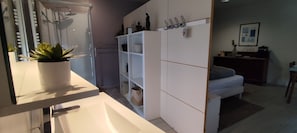 A modern bathroom with a shower, a sink, and a potted plant.