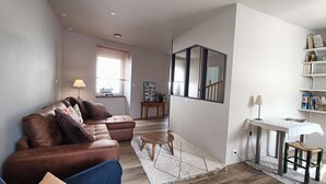 Un salon avec un canapé en cuir marron, une petite table en bois et un miroir au mur.