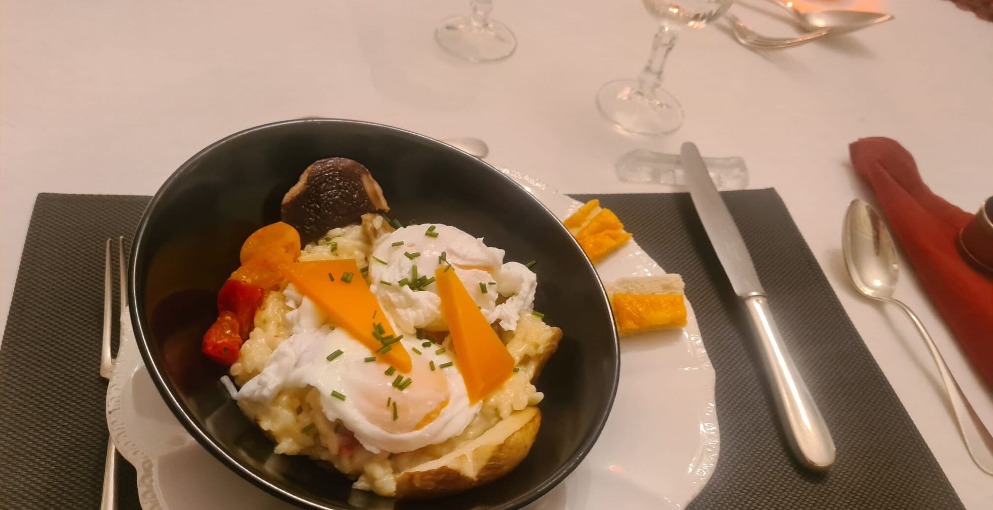 Un bol contenant divers aliments, notamment un œuf poché, des légumes et un morceau de pain.