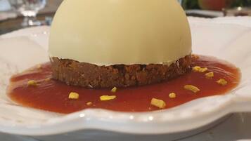 A dessert on a white plate with a red sauce and lemon zest garnish.