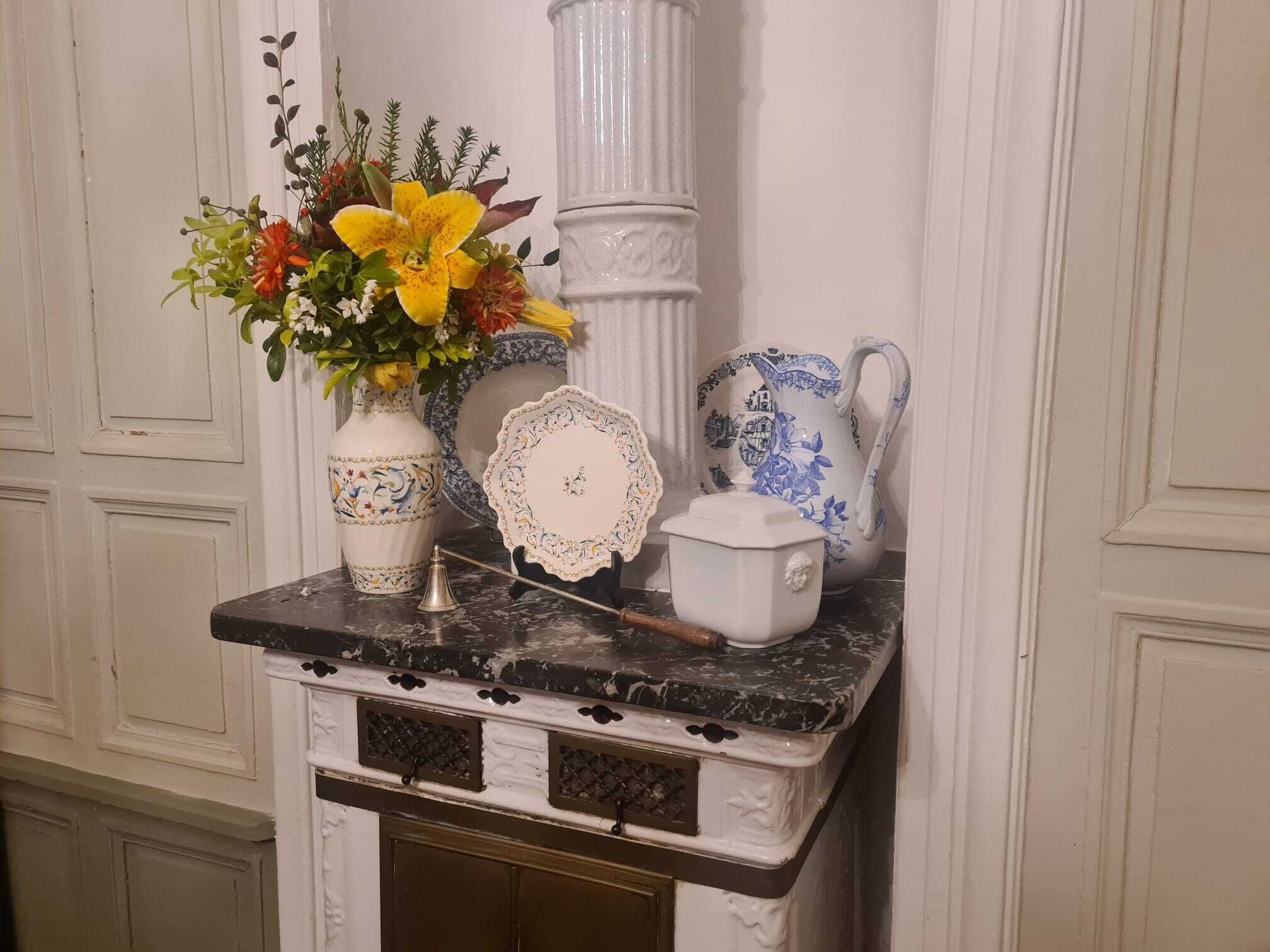 Una encimera de mármol con un jarrón de flores, un plato decorativo, una tetera y una jarra.