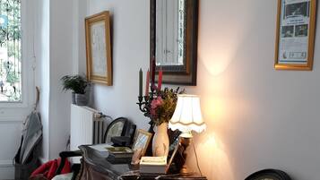 A room with a checkered floor, a wooden dresser, a chair, a lamp, a mirror, and a framed picture on the wall.