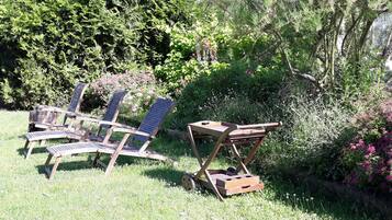 A garden with wooden chairs and a table.