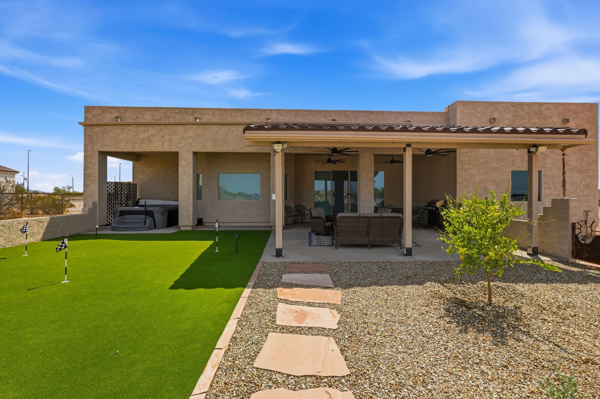 A modern house with a patio, a hot tub, and a well-maintained lawn.