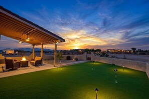 Un espacio exterior techado con césped artificial, una chimenea y asientos.