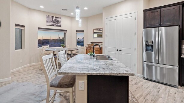 A modern kitchen with a central island, stainless steel appliances, and a view through the window.