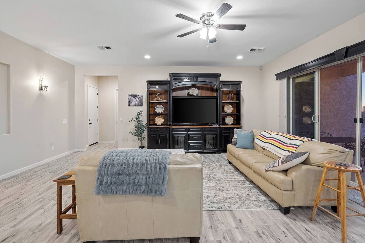 A spacious living room with a beige sofa, a coffee table, and a TV stand with decorative items.