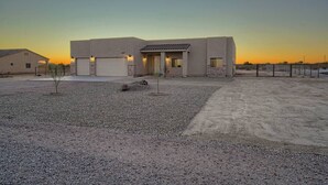 A modern building with a garage, a small patio area with a tree, and a gravel driveway.