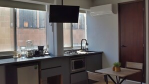 A compact kitchen with a built-in microwave, a sink, and a small dining area with a table and chair.