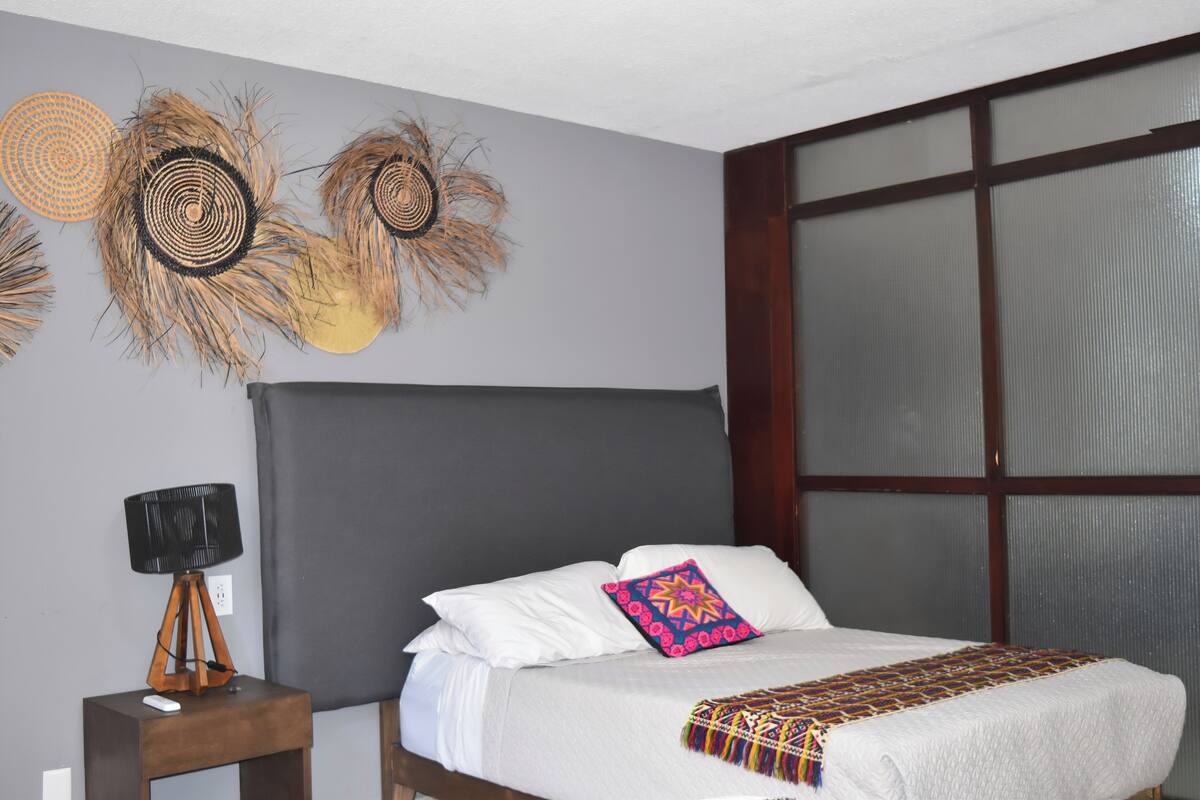 A bedroom with a large bed, a bedside lamp, and wall decorations.