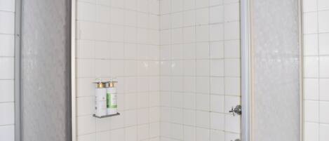 Ducha con cabezal de ducha de mano, dispensador de jabón y regulador de temperatura del agua.