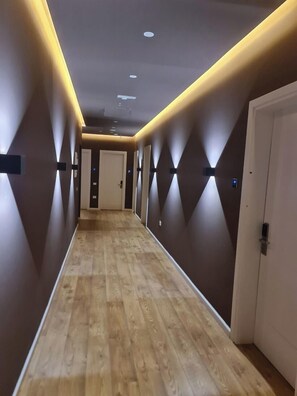 A hallway with wooden flooring, dark walls, and recessed lighting. - Star Hotel Astir (Kashar)