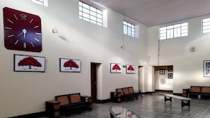 Un vestíbulo amplio con un reloj grande, varios bancos y obras de arte enmarcadas en las paredes.