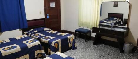 Una stanza con due letti, una scrivania, una sedia, uno specchio e una porta.