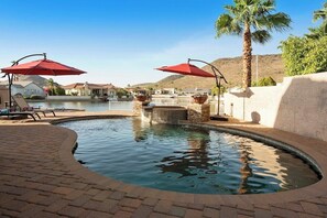 A swimming pool with red umbrellas, a brick pathway, and a view of houses and hills in the background. - Spectacular Lake House Retreat (Glendale)