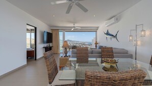 A modern living room with a glass dining table, wicker chairs, a sofa, and a view of the city.