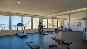 A gym with treadmills, stationary bikes, and weight machines, large windows with a mountain view.