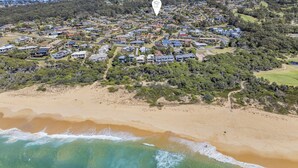 An aerial view of a coastal residential area with houses, a beach, and a golf course. - Sapphire Tides - Stunning Views (Tura Beach)