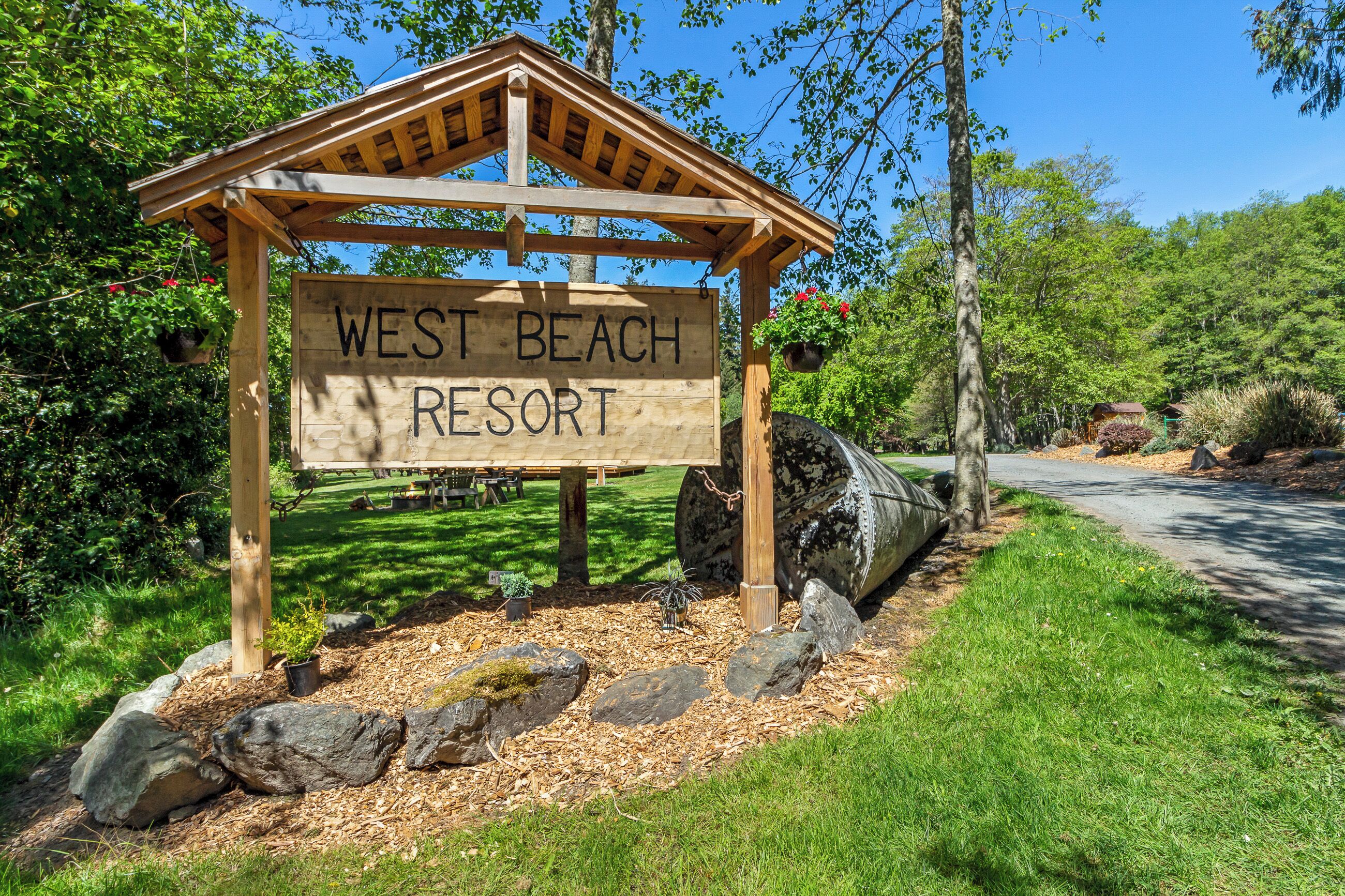 Un letrero de madera para el West Beach Resort.