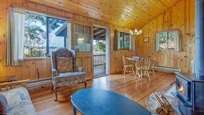 L’intérieur chaleureux d’un chalet avec des murs en bois, un coin repas, un canapé et une cheminée.