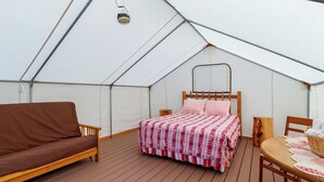 A tented room with a bed, a sofa, and a table with a basket.