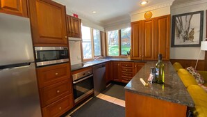 Cozinha moderna com armários de madeira, eletrodomésticos de aço inoxidável e uma grande janela com vista para o exterior.
