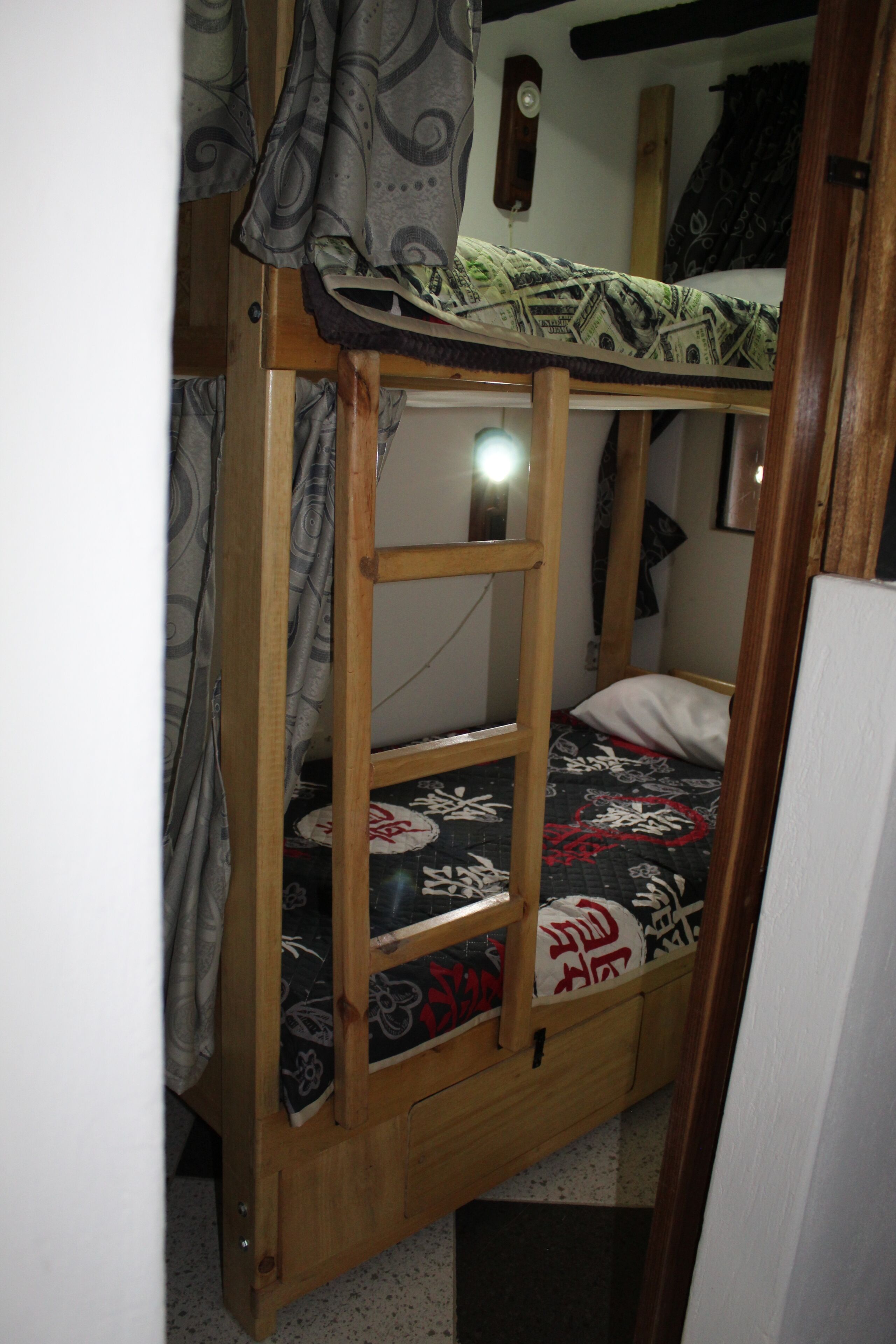 A bunk bed with a ladder, a bedside table, and a wall-mounted lamp.