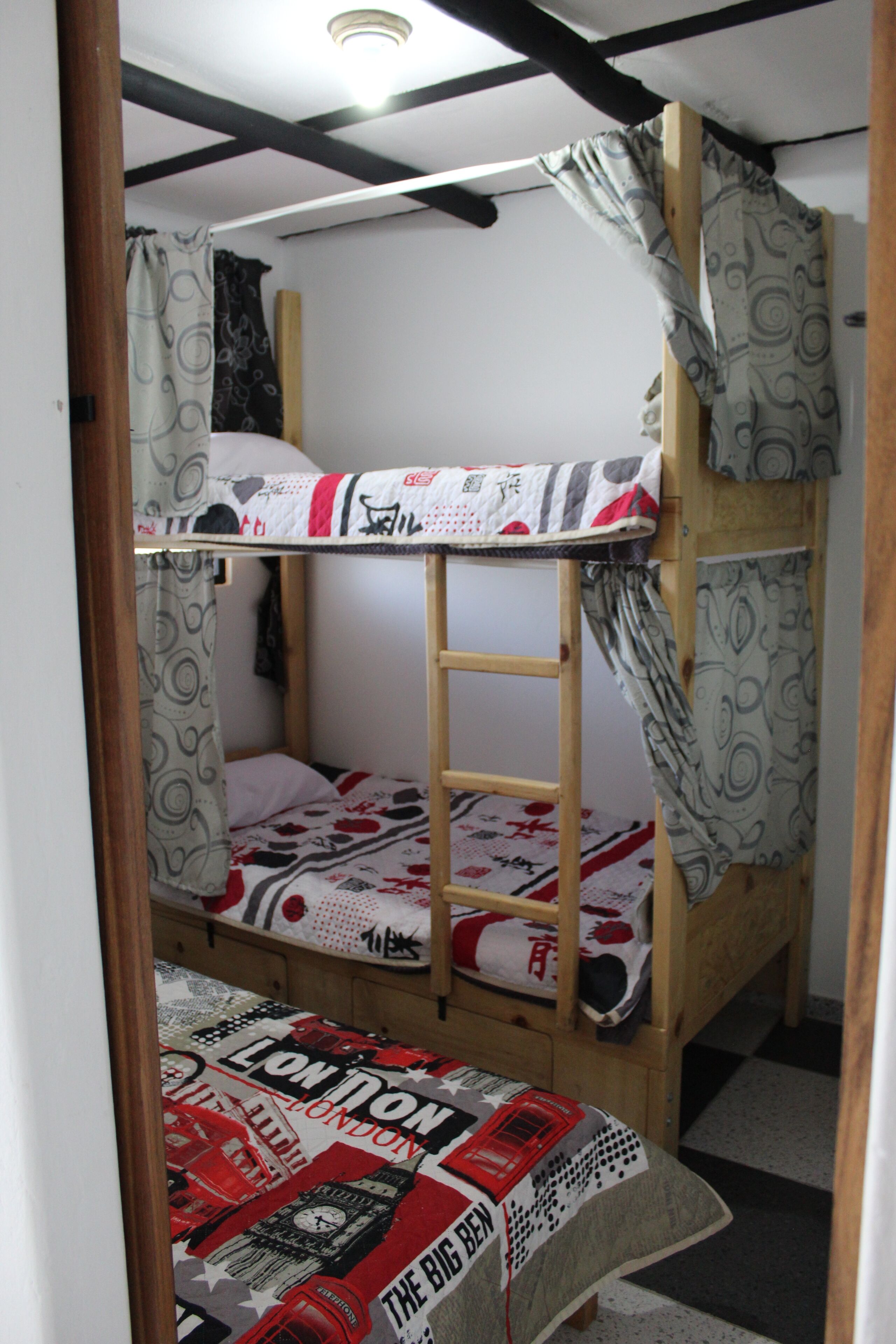 A bunk bed room with a ladder, patterned curtains, and a London-themed bedspread.